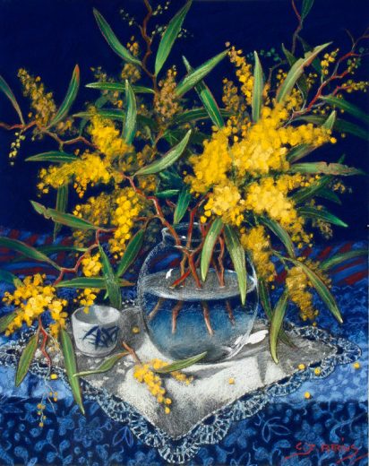 Wattle in a glass vase with embroidered cloth.