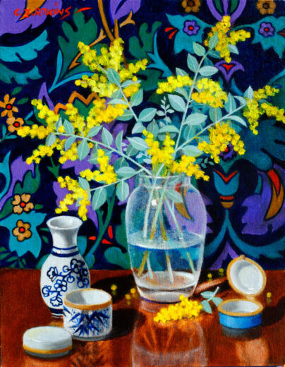 Yellow flowers in a glass vase in front of a complicated background.